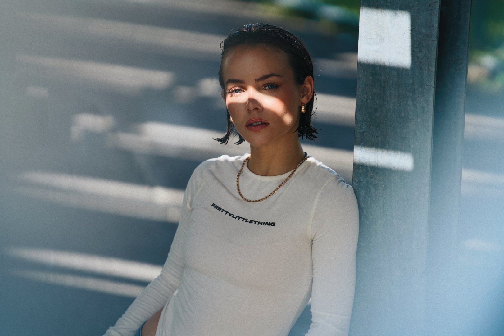Portrait of a model in white, cut by hard louvred daylight.